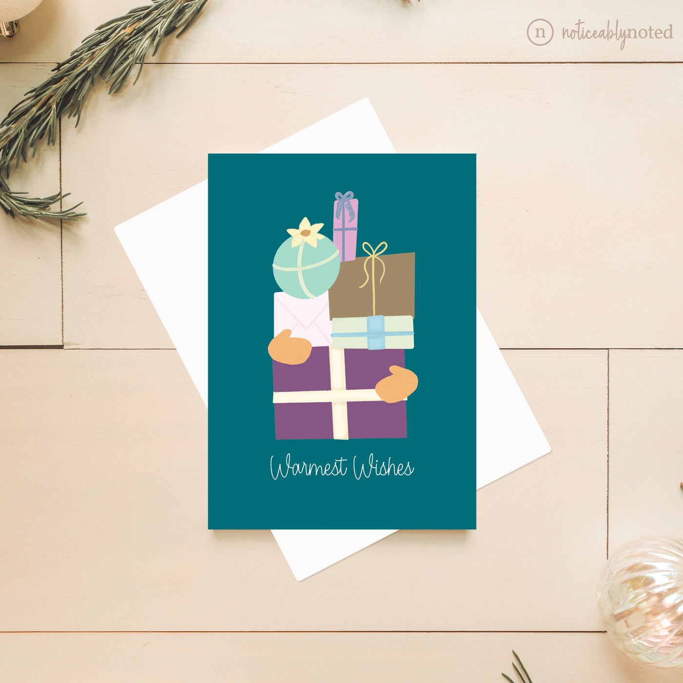 Greeting card with colorful gift illustrations and 'Warmest Wishes' text on a wooden surface.