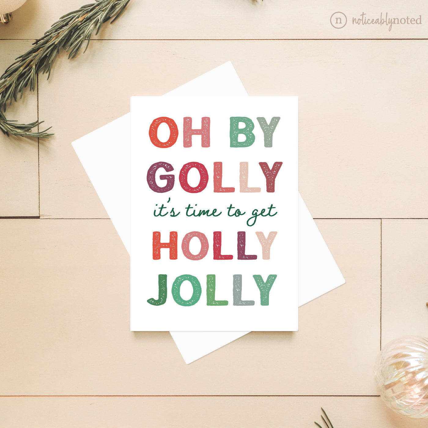 Christmas-themed card with colorful text on a wooden surface