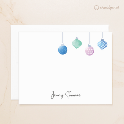 Note card with colorful Christmas ornaments and a name on a beige background