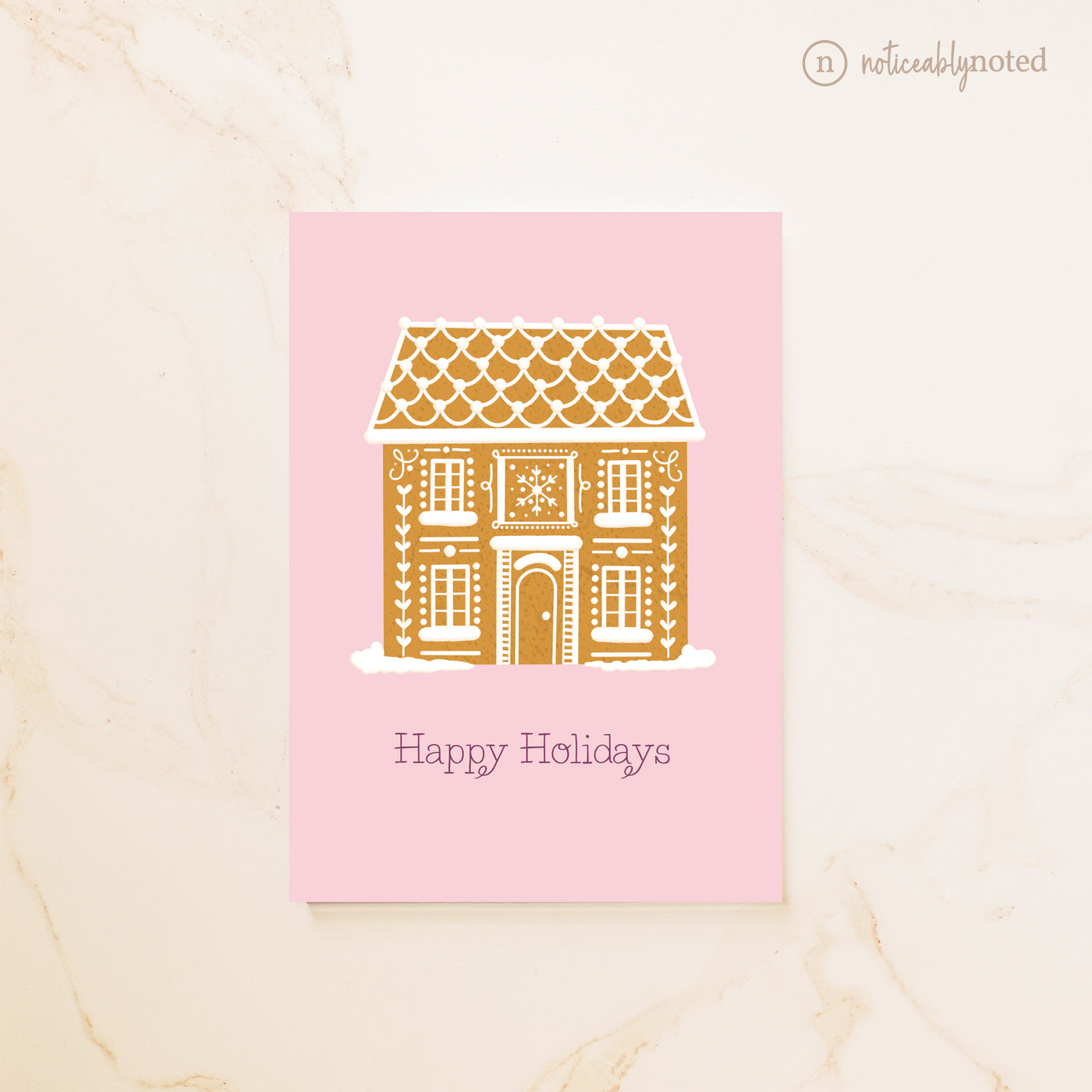 Greeting card with a gold gingerbread house design on a pink background