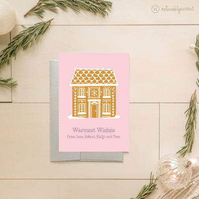 Greeting card with gingerbread house design on a pink background, surrounded by decorative elements.