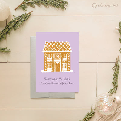 Greeting card with gingerbread house design on a light wooden surface with decorative elements.