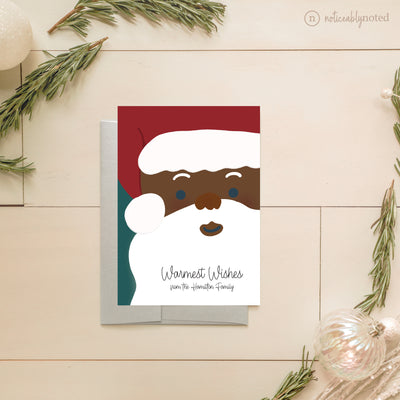 Christmas card with a cartoon Santa Claus face on a wooden surface with decorative elements.
