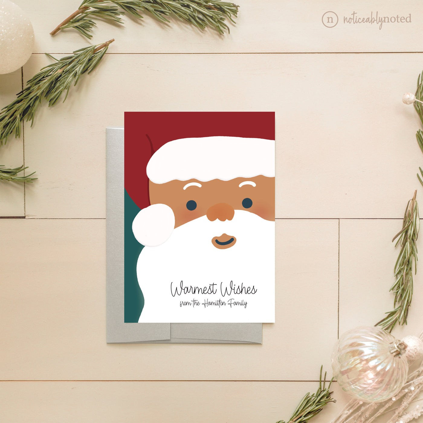 Christmas card with a cartoon Santa Claus face on a wooden surface with decorative elements.