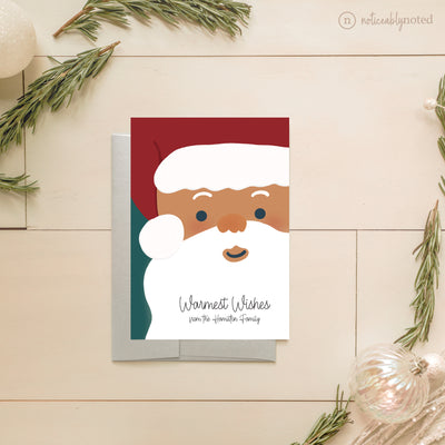Christmas card with a cartoon Santa Claus face on a wooden surface with decorative elements.