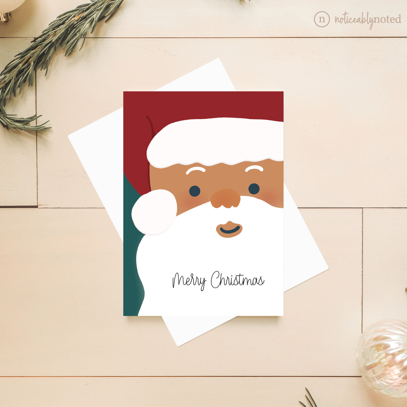 Christmas card with a stylized Santa Claus face and 'Merry Christmas' text on a wooden surface.