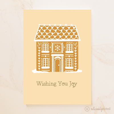 Greeting card with a gingerbread house design and 'Wishing You Joy' text on a beige background.